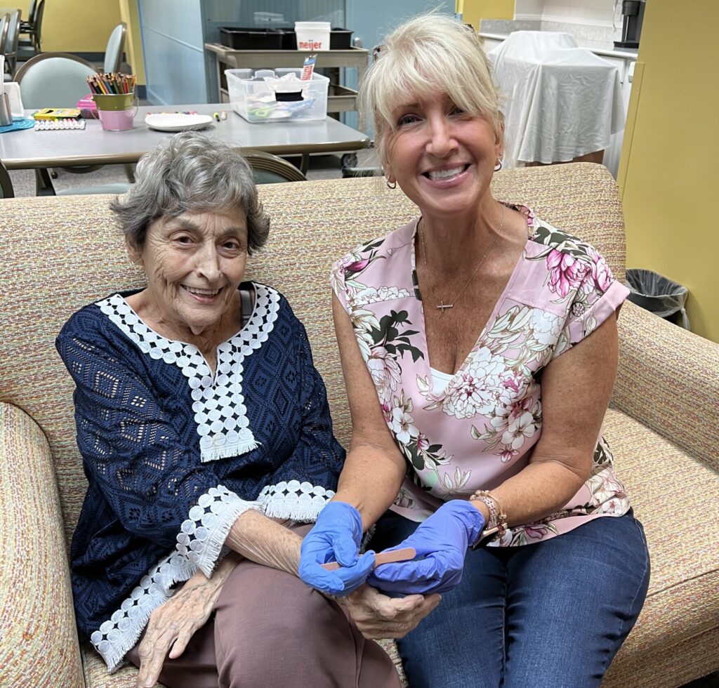 Two ladies smiling. Nurse is caring for a senior resident.